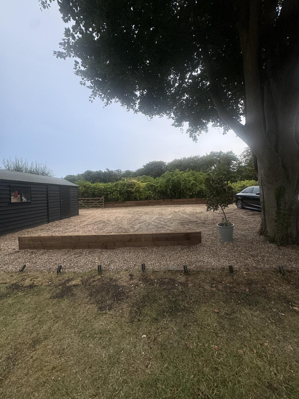 Gravel driveway with a long timber sleeper retaining wall leading up to a house