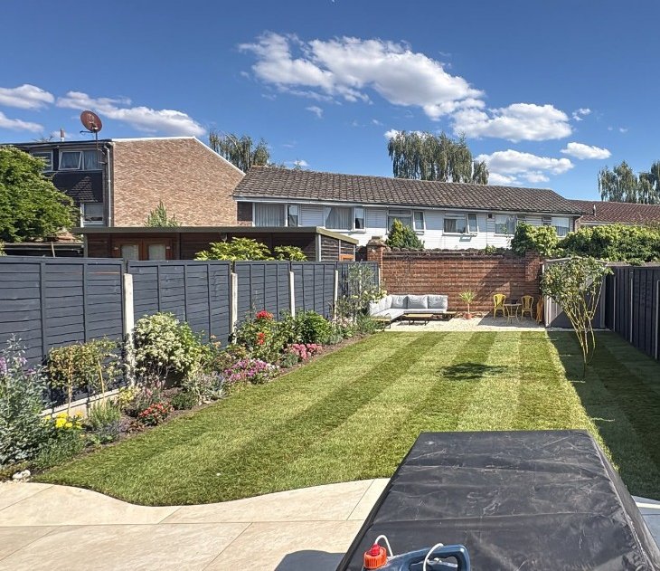 Newly laid lawn with mowing stripes next to planted borders